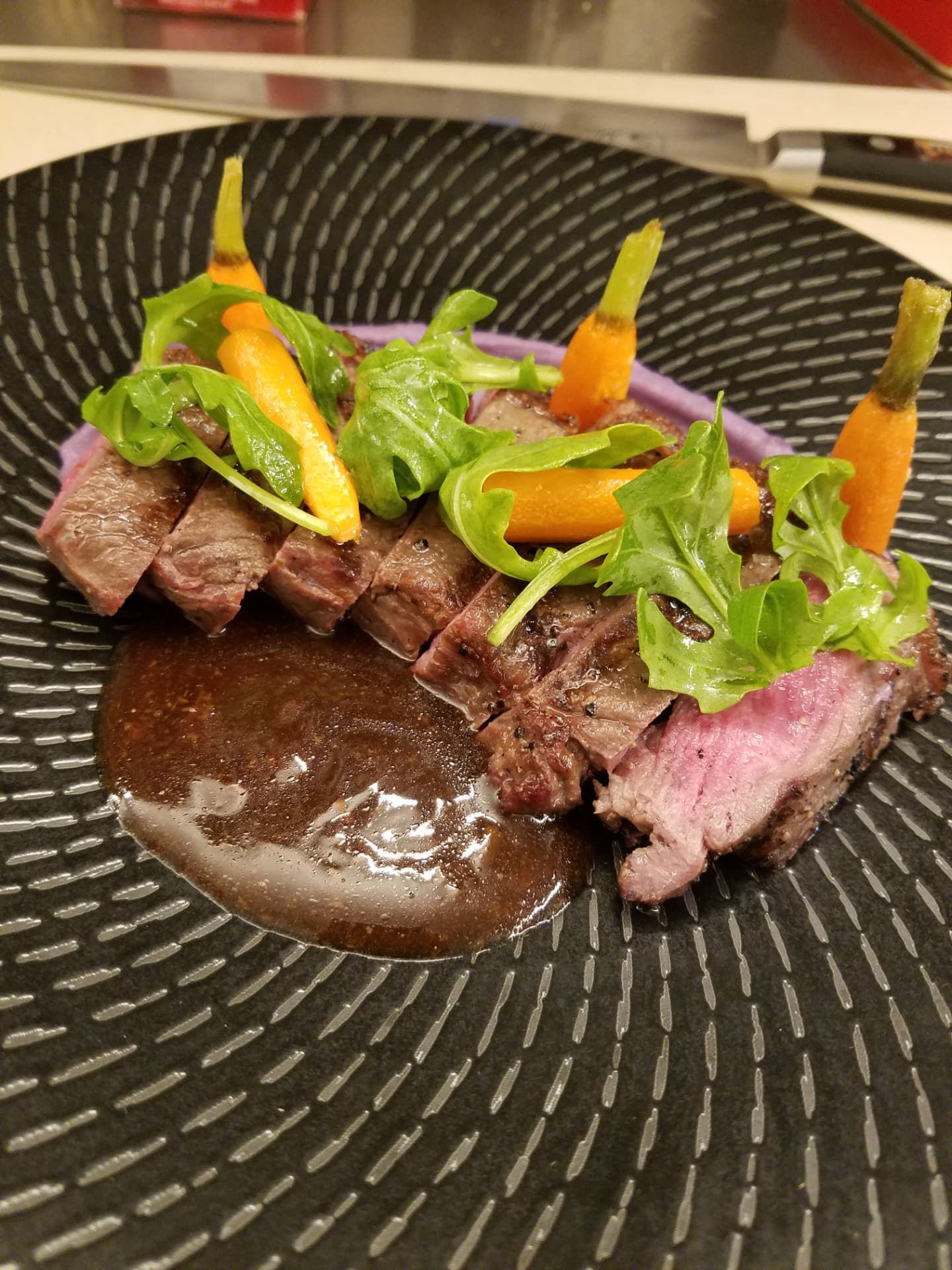 Sliced steak with carrots, greens and sauce