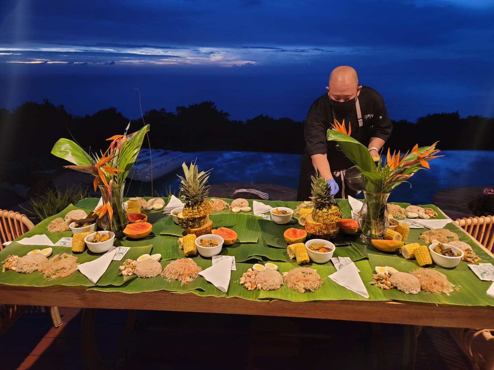Chef Dayne serving a private DYNE dinner at a long table at night