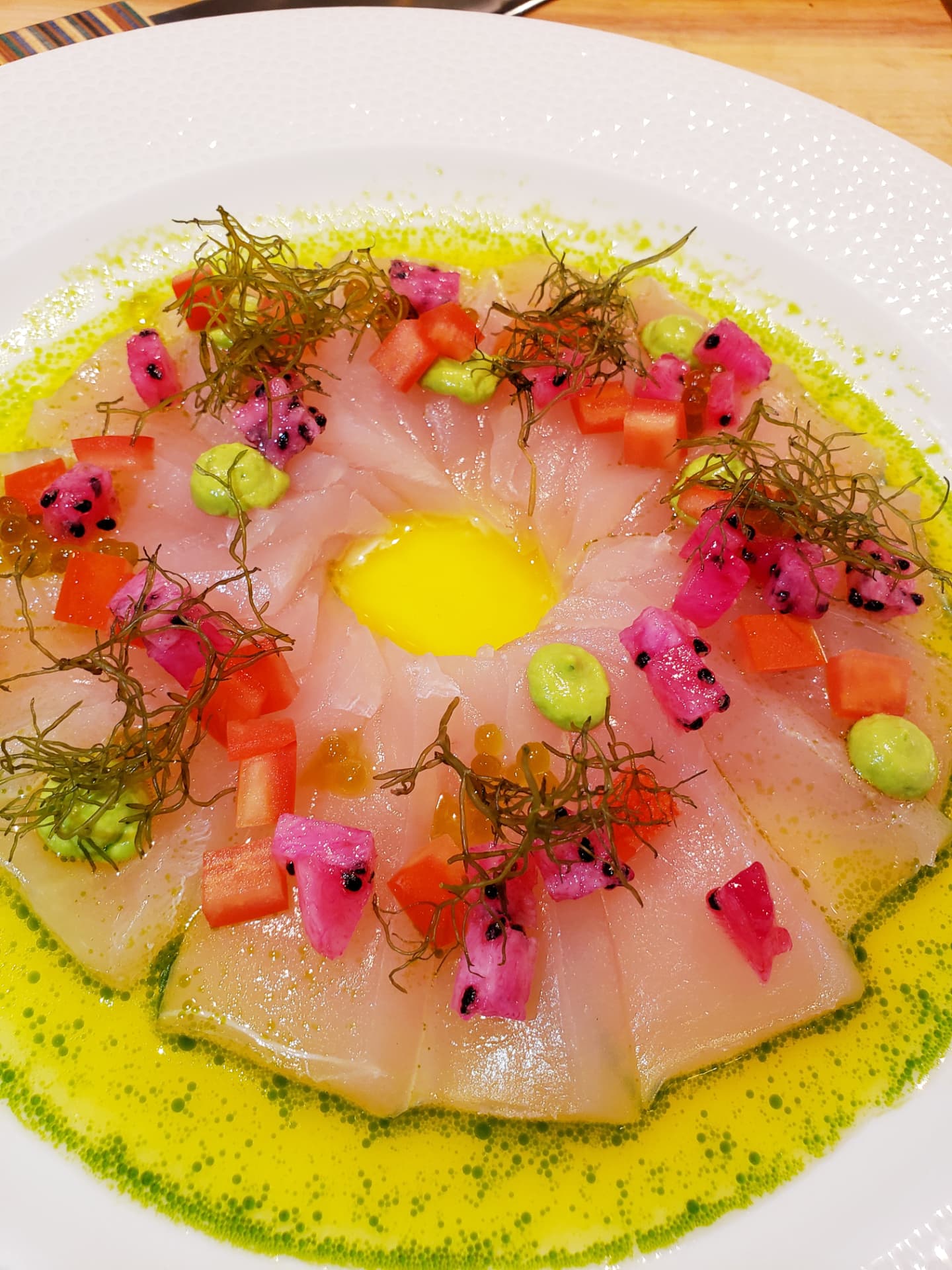 Thinly sliced fish crudo with dragon fruit and bright yellow sauce
